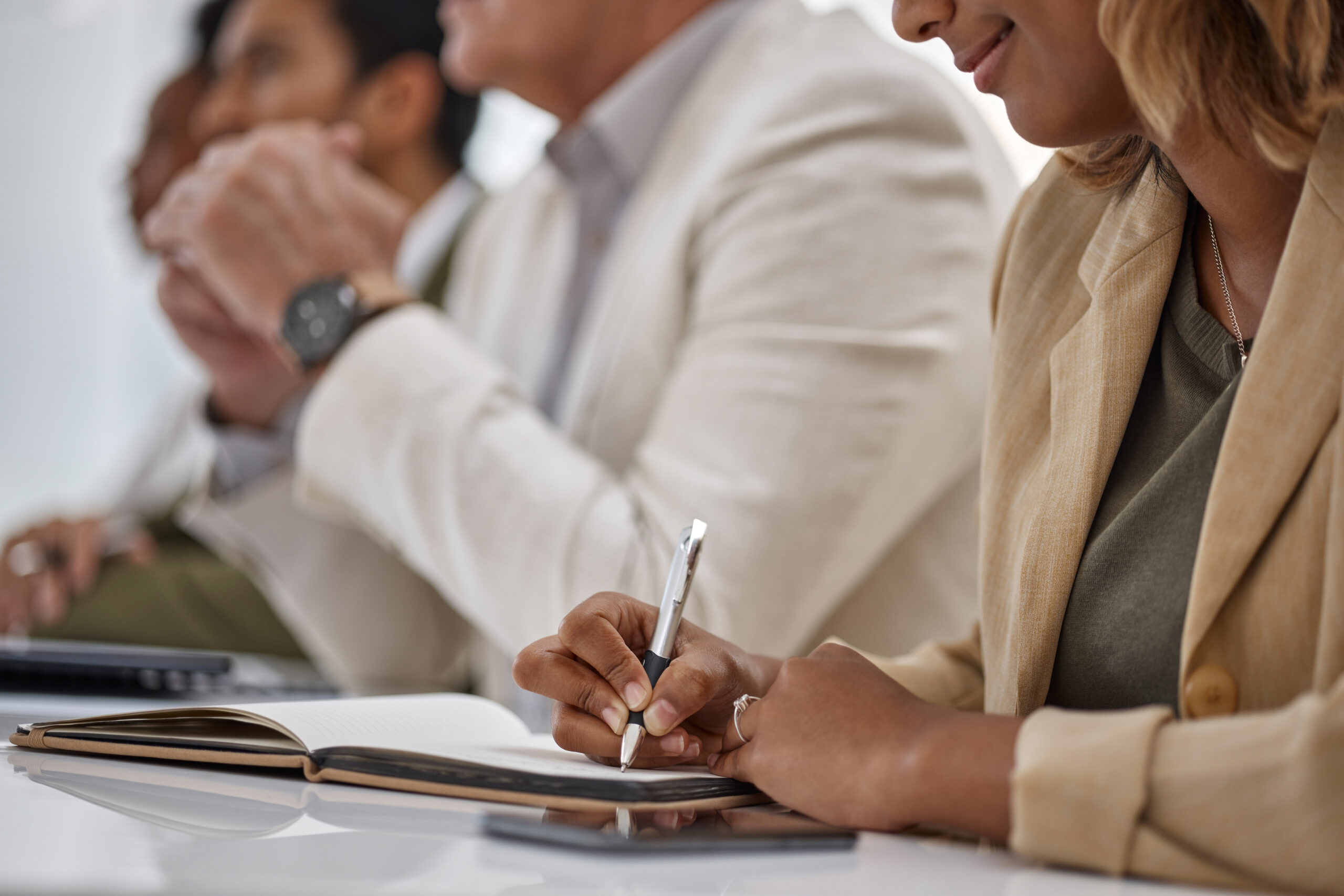 People sitting at a table listening and making notes