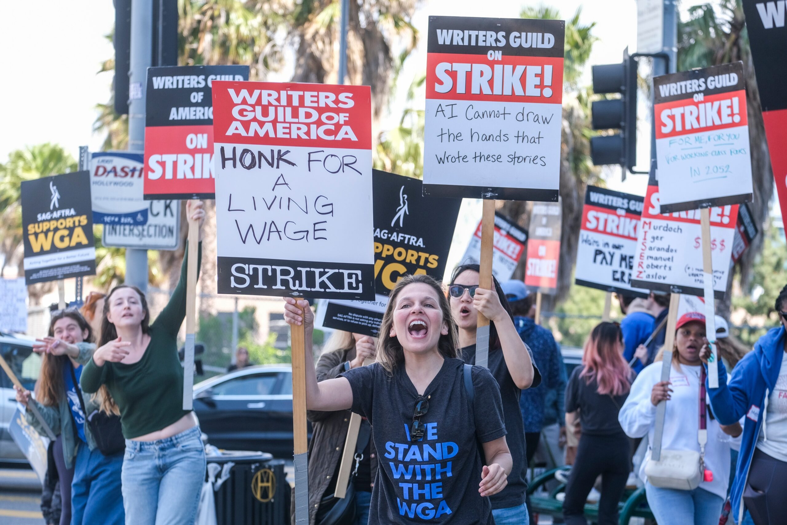 People with signs supporting the Writers' Guild strike